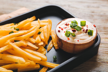 Plate with tasty sour cream and french fries on table