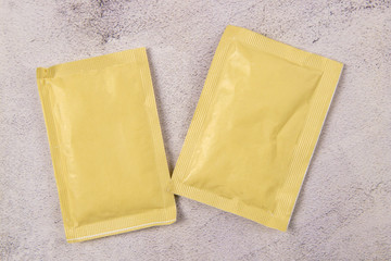 Two white paper sachets isolated on marble background. Top views with clear space