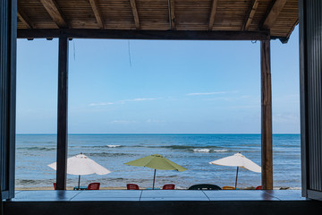View of a beach with umbrellas in the sand from a window.