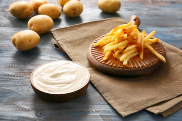 Tasty sour cream and french fries on table