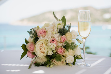 Glass of champagne and wedding flower composition in the restaurant by the sea