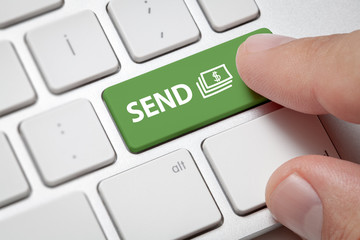 Male hand pressing computer key with send money