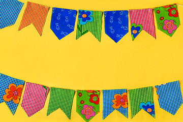 Multicolored fabric flags on a yellow background. Decorations for the holiday. Flatlay with space for text.