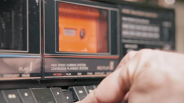 Inserting and removing an orange cassette tape from a vintage player. Angled shot.