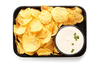 Plate with tasty sour cream and potato chips on white background