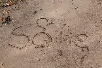 Fototapeta na wymiar The name Sofie written in the sand on the beach