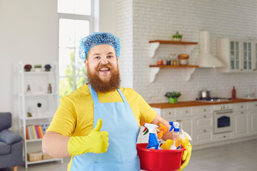 Funny fat man with a beard in an apron cleans the room in the house.