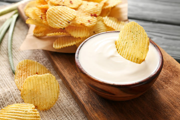 Obraz na płótnie Canvas Bowl with tasty sour cream and potato chips on table