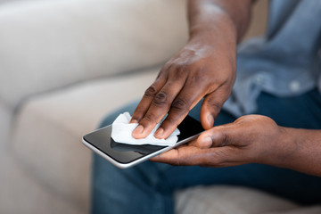 Unrecognizable African American Man Cleaning His Smartphone With Antibacterial Tissues