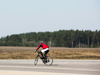 Fototapeta premium Joyful male bicyclist cycling in empty road during the coronavirus (COVID-19) pandemic lockdown, crossing the road, enjoying the view, copy space. Athlete cycling on the road. no cars.