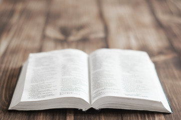 Obraz premium Open Bible. Holy Bible, Scripture. An open old book of the Holy Bible on the table. Rays of light shine on the book. Prayer and faith in God. Symbol of Christianity.