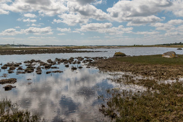 Some small lakes in a field where the sky makes a mirror image in the water