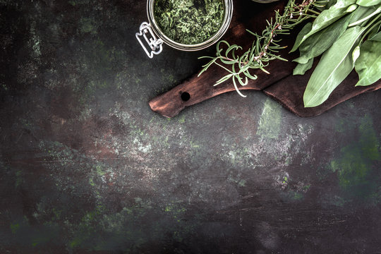Frische Bärlauchblätter mit Pesto und Rosmarin auf einem dunklem Küchenbrett. Dunkler Hintergrund.  Ansicht von oben. Freier Platz für Ihren Text.
