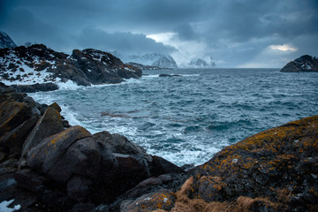 Lofoten islands, Norway. Dramatic view of Norge sea at winter day, snowy mountains and blue cloudy sky on background