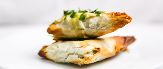 Handmade Greek Spinach and Feta Cheese Phyllo Spanakopita, isolated on white background with parsley. Baked and flaky