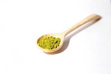 Green powder of Japanese matcha tea in a teaspoon. Matcha on a white background, isolated