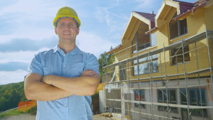 PORTRAIT: Contractor smiles in front of a modern house under construction.