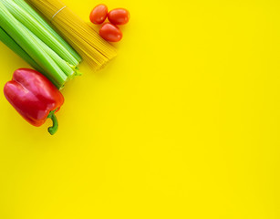 Fototapeta na wymiar Coronavirus food supplies concept. Food layout with pasta, tomatoes, bell pepper, celery on yellow background. Flat lay. Copy space