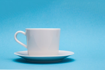 white cup on a saucer on a blue paper background
