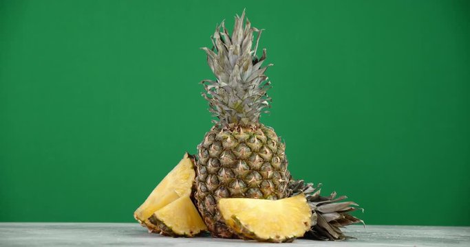 Pineapple with greens and sliced pineapple rotates slowly.