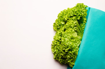 Fresh lettuce salad leaves lying in a turquoise ecologic bag on a white background. Place for text.