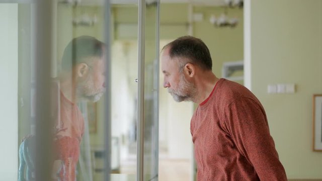 Mature man in the Museum at the exhibition of sculpture examines the exhibits