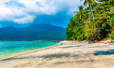 Tropical beach at Ko Lipe island, Thailand. Part of Tarutao national nature park. Beautiful beach, white sand, turquoise sea. Exotic vacation, tropical paradise. Trees and palms on beach.