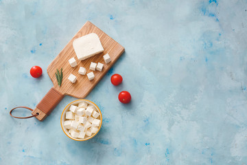 Board and bowl with tasty cut feta cheese and tomatoes on table