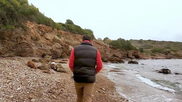 &Mu;an walks on beach in winter, trees, rocks and cloudy sky, Lavrio Greece