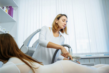 Young woman on a massage procedure in beauty salon. Woman in special white suit getting anti...