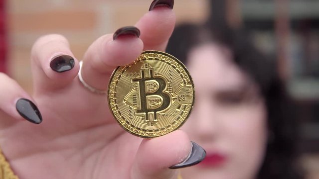 Young lady showing golden bitcoin cryptocurrency.