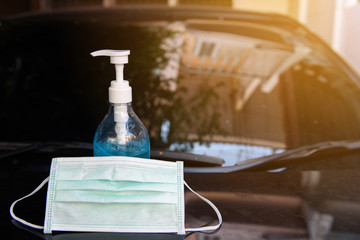 Blue ethyl alcohol hand gel pump bottle and surgical face mask place on the black car in front of the house, idea, and concept of coronavirus, covid19