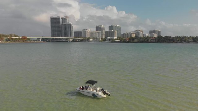 Epic aerial view of North Beach Miami in the background and a boat floating in the waters of Haulover Sandbar in the foreground
