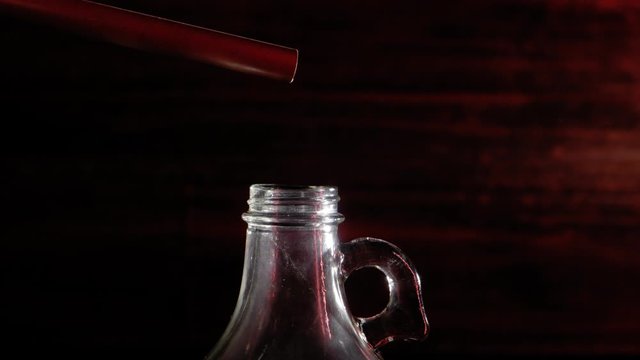 MOONSHINE BEGINS DRIPPING FROM A STILL, INTO A GLASS JUG.  ECU SLIDER SHOT IN 4K.  NO PEOPLE.