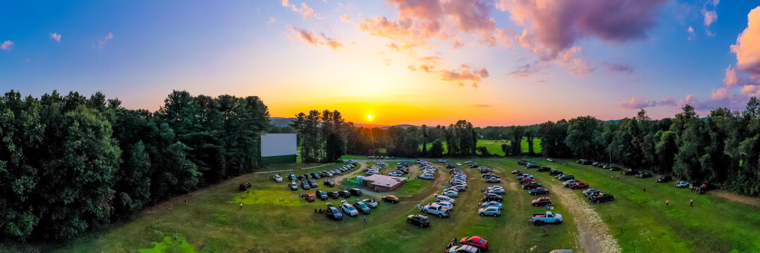 Panorama Of Outdoor Drive-in Movie Theater At Sunset With Cars Parked In Field. Aerial Photo Taken At Northfield Drive-In.