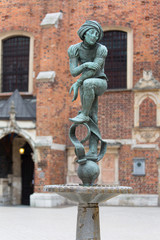 Fototapeta na wymiar Figurine student, a copy of the form from the altar of Veit Stoss, fountain in the square of St. Mary's, Krakow, Poland