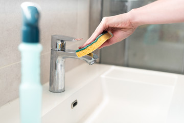 woman cleaning service. wiping bathroom wash basin with sponge