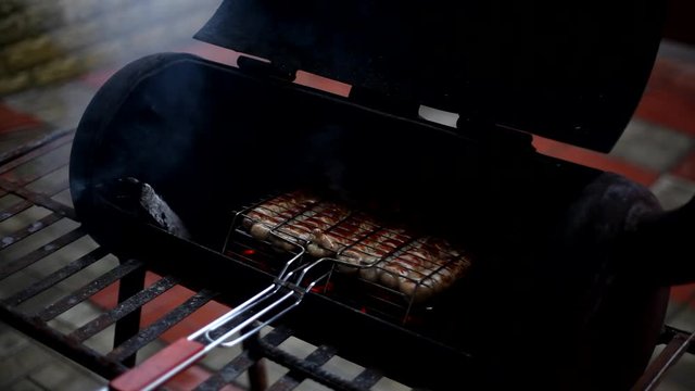 Cooking sausages in the grill. Smoking juicy meat sausages on the metal grate on the open barbecue.