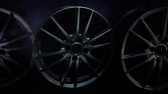 Beautiful designer car alloy wheels on a black background with smoke, copy space, luxury