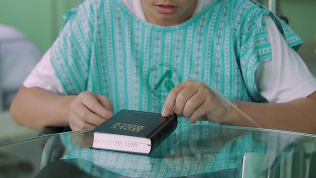 A male handicap approaches a Bible on a glass table.