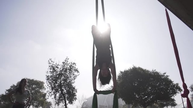Woman practicing air skills upside down outdoors.
