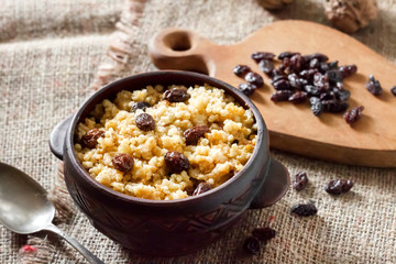 Sweet millet porridge with dark raisins in ceramic rustic bowl
