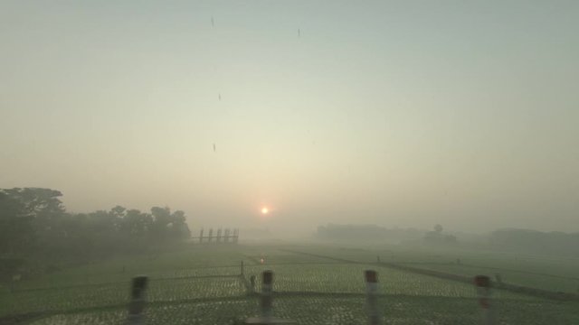 the footage was taken from behind the glass window of a car while traveling. the sun is rising and theres fod due to winter.