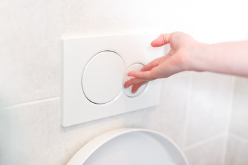 Woman hand flushing toilet button - press the water button, flush the toilet, health concept