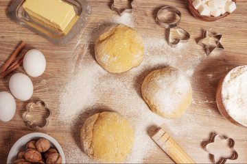 Background of dough and ingredients for baking sweet cookies or cakes. Eggs, flour, butter, sugar, spices and cooking utensils on a wooden table. Pastry making and bakery concept. Top view