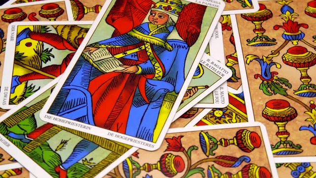 A hand putting down, 'Tarot de Marseille, whole major arcana set, on rotary table. Tokyo, Japan. March, 2020. Camera fixed, close-up, high angle view.