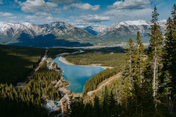 Top/Aerial view of Rundle Forebay Reservoir surrounded by forests and Canadian Rockies on background with Canmore town. Grassi Lakes, Alberta, Canada