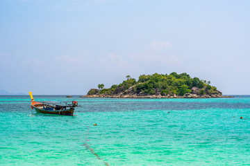 Obraz premium Long tail boats in small harbor at Ko Lipe island, south Thailand. Tropic and exotic island is symbol of tropical paradise, part of Tarutao national nature park. Vibrant colors, turquoise water.