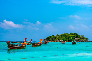 Fototapeta na wymiar Long tail boats in small harbor at Ko Lipe island, south Thailand. Tropic and exotic island is symbol of tropical paradise, part of Tarutao national nature park. Vibrant colors, turquoise water.