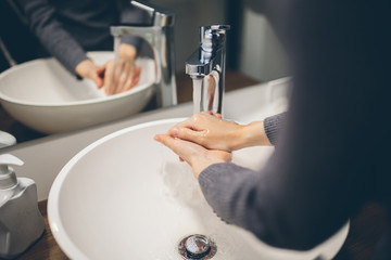 Obraz na płótnie Canvas Young woman wash hands with soap in bathroom. Trendy coronavirus covid-19 concept